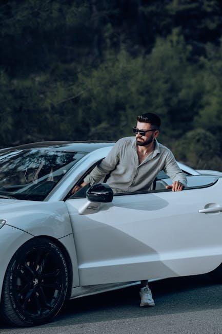 Confident man steps out of a sleek white car, embodying modern luxury.